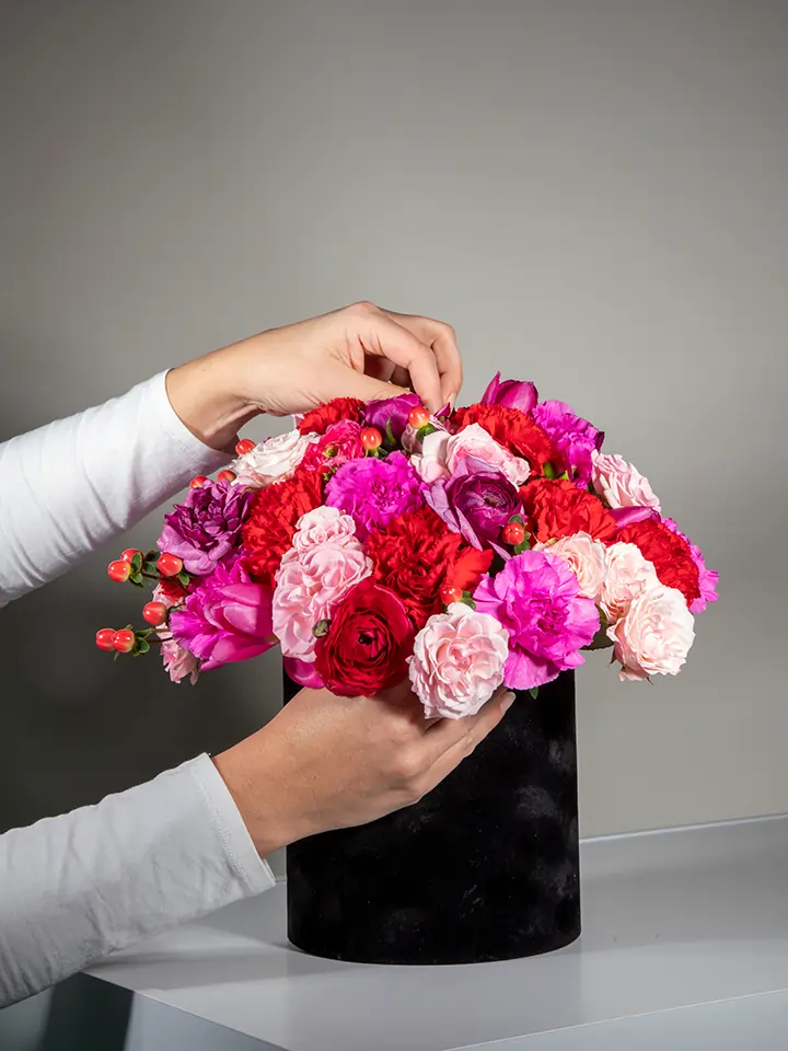 Flower box nera di fiori rossi fucsia rosa in mano